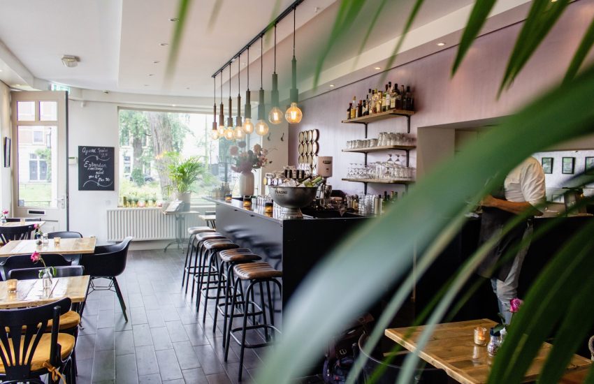 An interior shot of a cafe with chairs near the bar with wooden tables