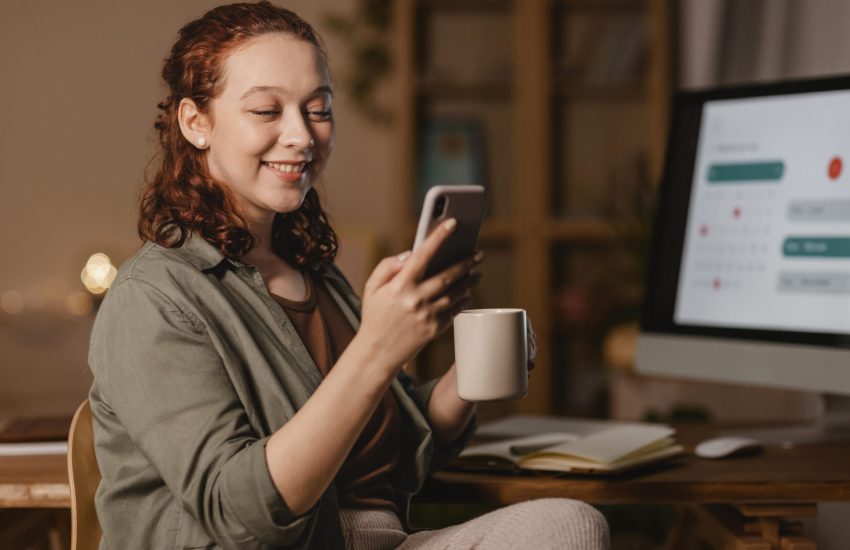 woman-home-using-smartphone-front-computer-while-having-coffee